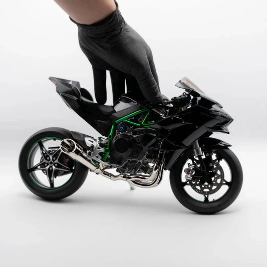 Main posée sur la Kawasaki H2R miniature sur fond blanc.